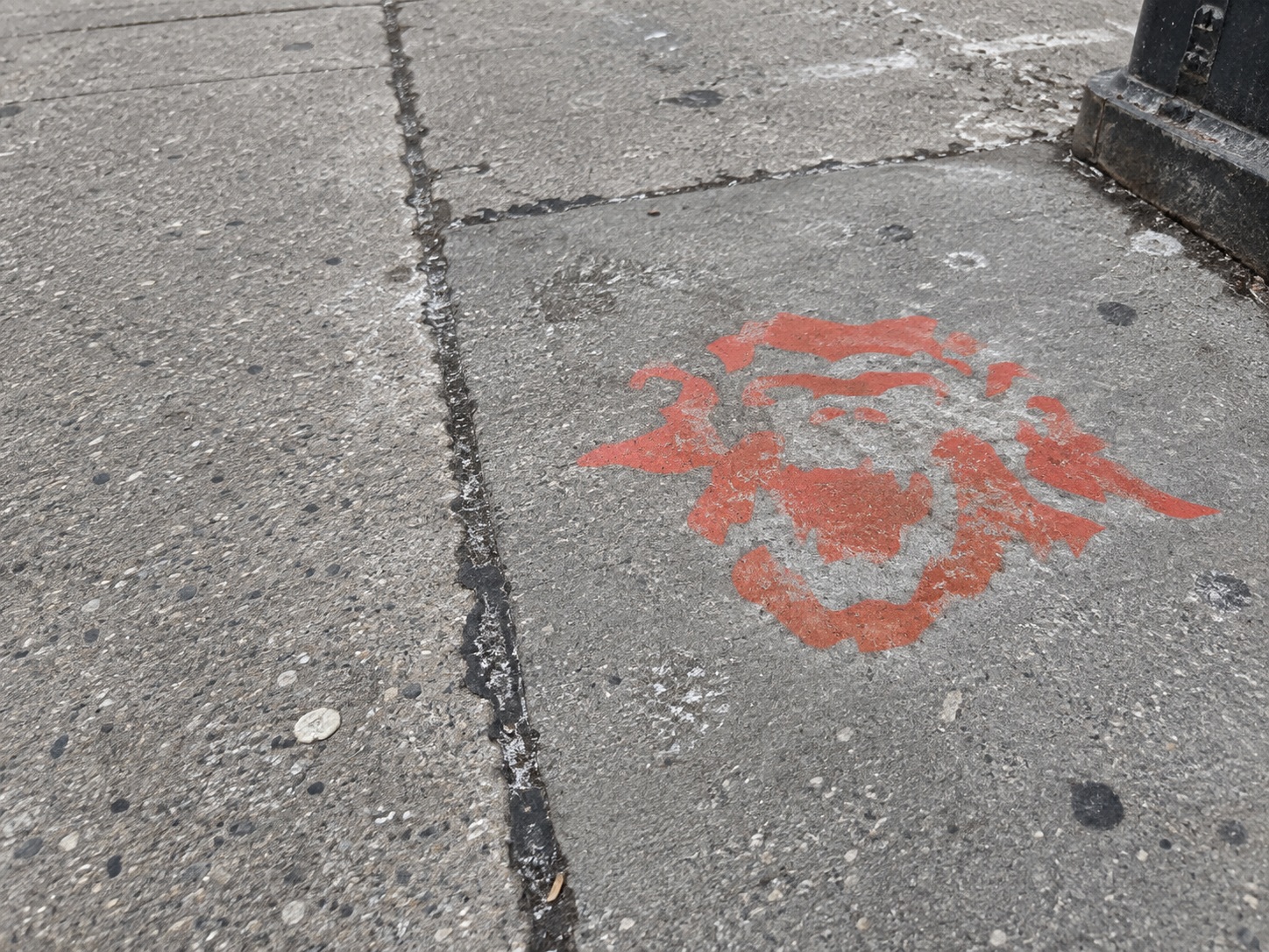 A worn painted TORON10 mark beside patched asphalt and salt stains.
